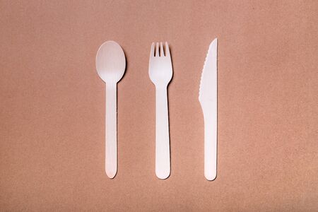 Set of wooden bamboo cutlery: fork, knife and spoon on natural paper background.