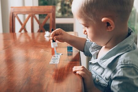 Little boy laboratory activity with colored water, pipette and pieces of glass. Homeschooling concept.の写真素材