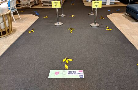 Distance stickers and signs fixed over the floor at the shop queue for the people to follow social distancing to avoid infection of coronavirus disease.の写真素材