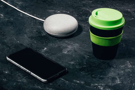 Digital Assistant concept. Smart speaker with LED lights activated on concrete black table with...