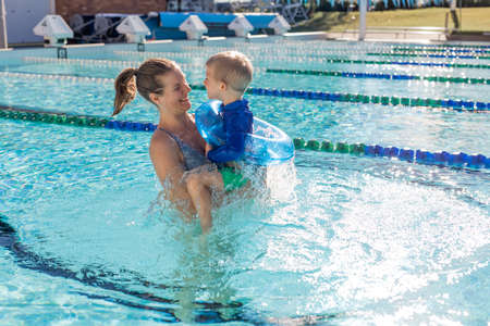 Mother and little boy in swimming pool outside in sunny day, smiling face, enjoy in the water, close up portrait.の写真素材