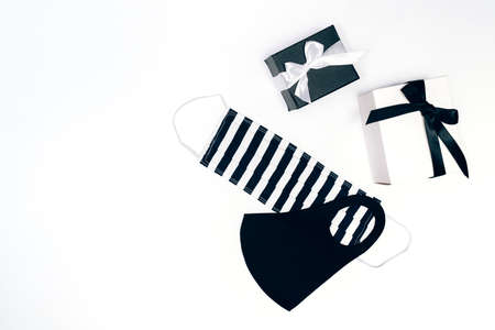 Black and white gift or present boxes, handmade facial masks on white background. Flat lay composition for birthday, Christmas, wedding. Social distansing.の写真素材