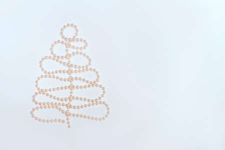 Pearl beads in Christmas tree shape on white background. Flat lay composition for Christmas, New...