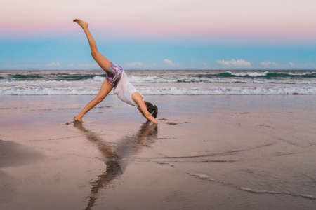 Young beautiful sportive woman doing exercises on beachの写真素材