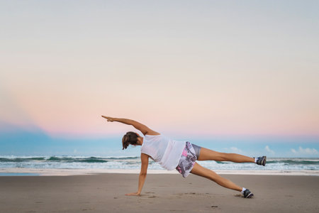 Young beautiful sportive woman doing exercises on beachの写真素材