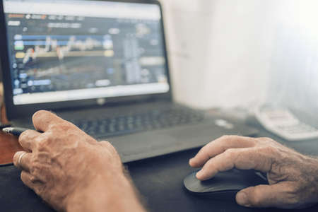 A senior man sitting at a desk in front of a laptop computerの写真素材
