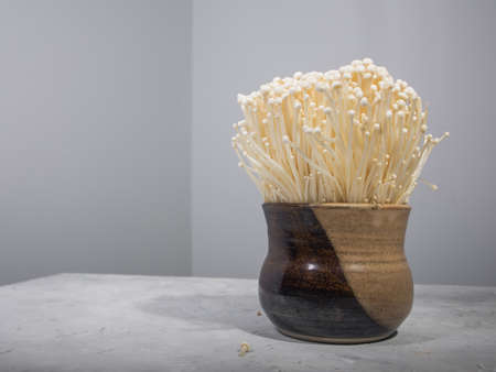 Enoki mushrooms in clay bowl on table