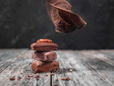 Dark handmade chocolate stack with dry leaf and cacao chipsの写真素材