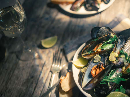 Blue mussles with vine and baguette on wooden tableの写真素材