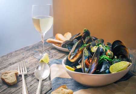 Blue mussles with vine and baguette on wooden tableの写真素材