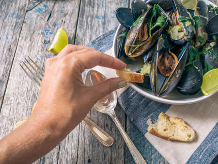 Blue mussles with vine and baguette on wooden tableの写真素材