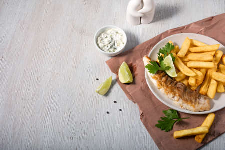 Fish and chips with lemon, parsley and sauce