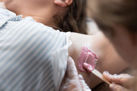 Hand of cosmetologist applying wax paste on armpit.の写真素材