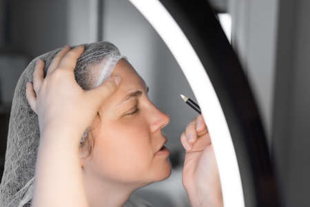 Coloring the eyebrows and eyelashes with henna in a beauty salon.の写真素材