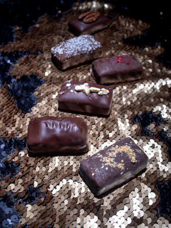 Assorted dark handmade chocolate on the sequinsの写真素材