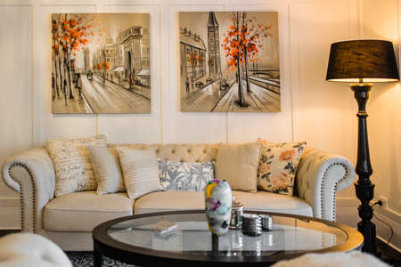 Big and comfortable living room with bright sofa and paintings on the wallsの写真素材
