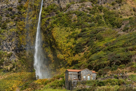 Small stone house in the mountains with waterfall next to it at Flores Island Azores Portugalの写真素材