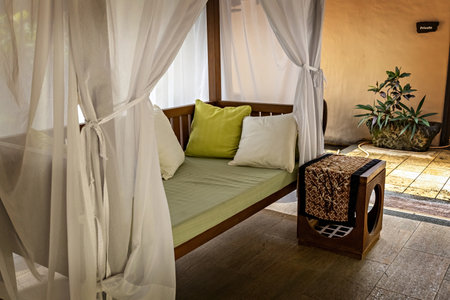Private guest area in luxury hotel with sun bed, white curtains and bed tableの写真素材