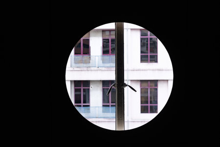 Circular window framing a modern apartment building facade with symmetrical windows.の写真素材