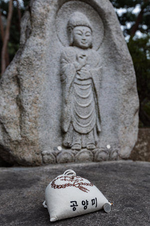 Offering pouch placed before a carved stone Buddha statue at a temple site in Seoul, South Koreaのeditorial素材