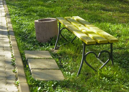 Elements of urban park architecture - a wooden bench with a wrought heart for lovers, lawnの写真素材