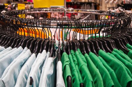 Clothing store. Bright things hang neatly on the black shoulders. Assortment, fashion, shopping, consumption, style, seasonal wardrobe renewal, competent formation of capsule wardrobe, lifestyle.の写真素材
