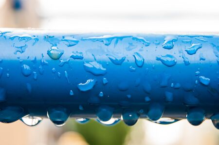 Raindrops on a blue metal pipe.の写真素材