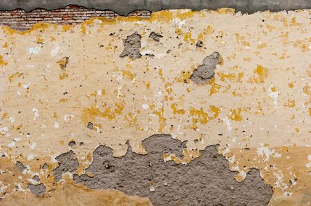 Orange decorative background. In the photo there is a wall with peeling paint and plaster parts. I really need a repair. Poverty, devastationの写真素材