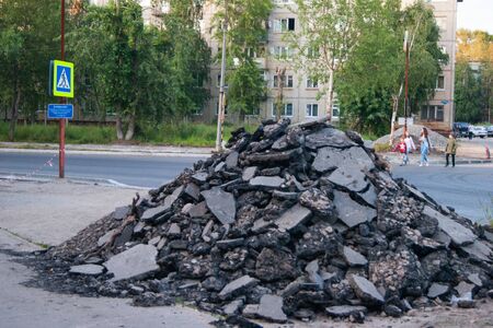 Road works - on the side of a recently made road, on the sidewalk lies a mountain of pieces of broken asphalt. Poverty, poverty, CIS, negligence, devastation, desolation, Russiaの写真素材