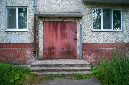 Red door to the utility room for storing equipment of janitors in a five-story city building. Storage room. horizontal photoの写真素材