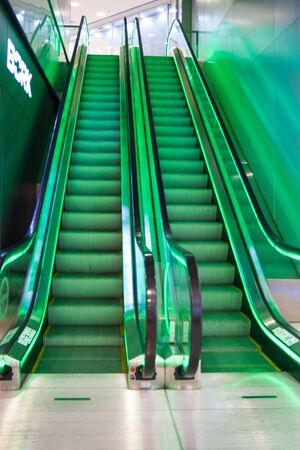 Two empty escalator stairs are illuminated with green light. Descent and ascent. Deserted....