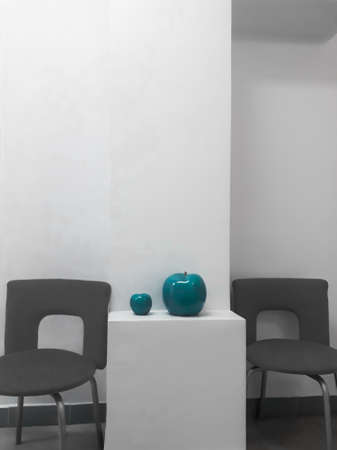 Details of the interior - a white wall, office chairs and two ceramic apples of turquoise color.の写真素材