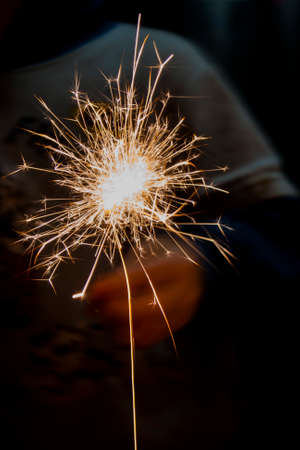 Burning Bengali fire on a dark background in a childs hand, make a wish for the new year, Christmas miracles and divination, baptism. Traditionsの写真素材