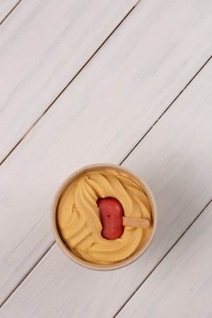 Natural peach ice cream in a craft bucket with raspberry ice lolly frozen inside, copy space, top viewの写真素材