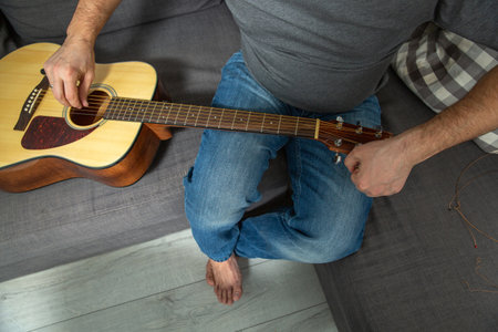 A man tunes an acoustic guitar