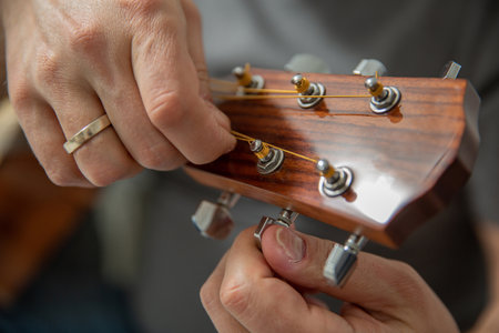 A man tunes an acoustic guitar, selective focus
