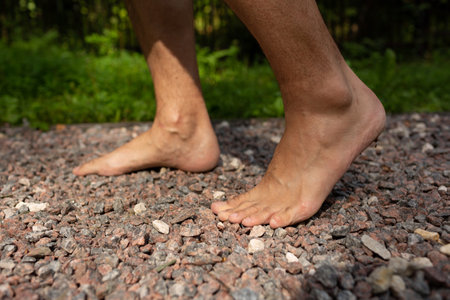 A man walks barefoot on fine sharp gravel, foot massageの写真素材