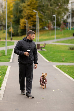 A man walks in the park with a dog and coffeeの写真素材