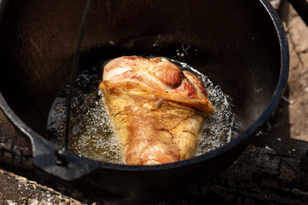 The process of cooking pork rolls in a cauldron over a fireの写真素材