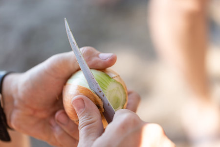 A man cleans onions, preparing vegetables in field conditionsの写真素材