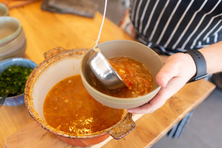 Cook pours soup into a plate