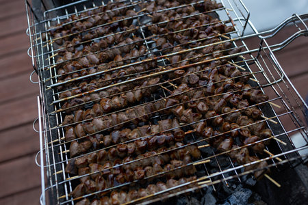 Chicken hearts in sauce on wooden skewers are fried on the grillの写真素材