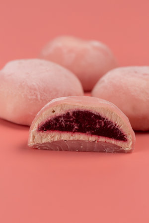 Traditional Japanese dessert, mochi cake in thin pink rice dough on a pink background with pink filling, cut, open spaceの写真素材