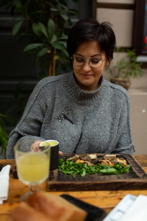 A beautiful brunette woman in a cozy warm sweater is sitting at a table in a restaurant