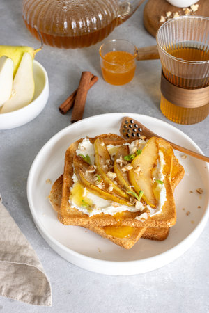 Breakfast with cream cheese toasts and caramelized pears, honey and walnutsの写真素材
