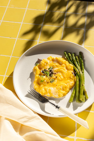 Scrambled eggs with asparagus on a sunny morning on a yellow backgroundの写真素材