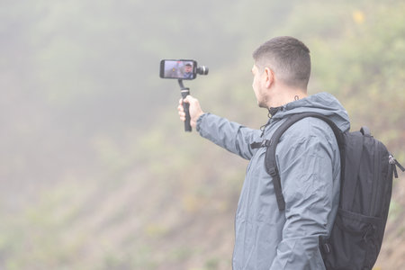 A man records a video for a blog on a foggy day