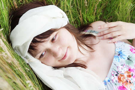 Young Woman Laying on Field Grass Portraitの写真素材