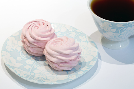 Delicious homemade raspberry marshmallow with black ceylon tea, served on beautiful blue and white plte and cup.の写真素材
