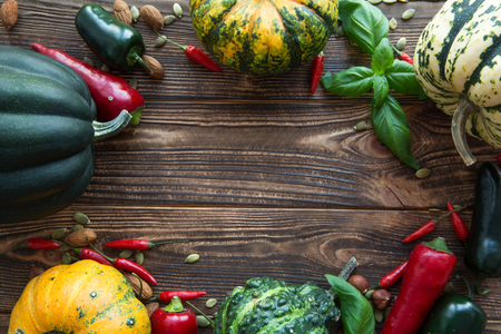 Thanksgiving day concept background. Pumpkin frame, assortment of pumpkins, space for text. Pumkinns on brown wooden background. Copy space for greeting.の写真素材